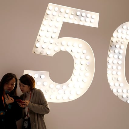 Visitors use their smartphones as they stand next to a large 5G display inside Xiaomi Corp’s booth at MWC Barcelona, the world’s biggest mobile industry exhibition, in Spain in February of last year. Photo: Reuters