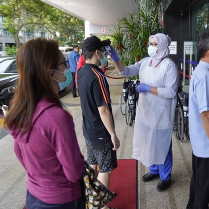 Nurses check the temperatures of visitors as part of the coronavirus screening procedure at a hospital in Kuala Lumpur. Photo: AP