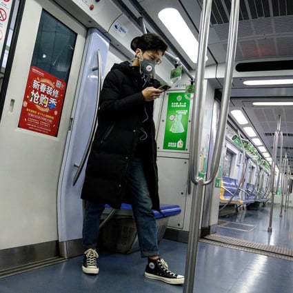 A man wearing a protective face mask to help stop the spread of a deadly SARS-like virus which originated in the central city of Wuhan uses his mobile phone inside a train in Beijing on January 28, 2020. Photo: AFP