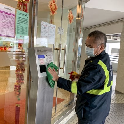 A security guard at Whampoa Garden disinfects the entry key pad outside the building. Photo: Minnie Chan