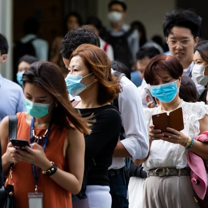 People wearing protective masks stand in line for a temperature check outside an office building in Singapore. Photo: Bloomberg