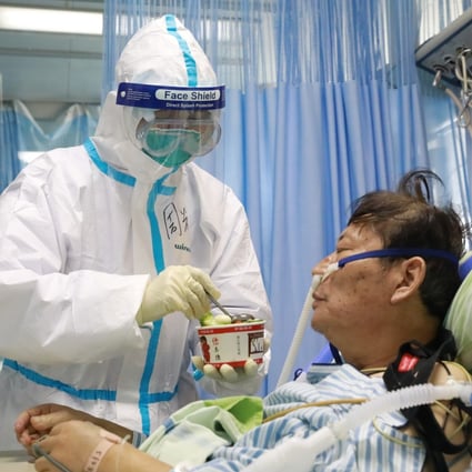 A nurse in a protective suit feeds a coronavirus patient in an isolated ward in Wuhan. Photo: Reuters