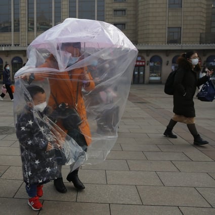Masks, umbrellas – and even plastic bags. People take precaution against the coronavirus outbreak at the Beijing railway station on Tuesday. Photo: EPA-EFE