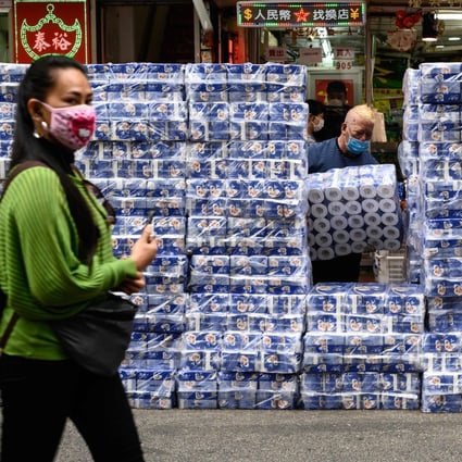 A woman wearing a protective face mask walks past stacks of toilet paper for sale in the Tsuen Wan district of Hong Kong on February 8. The Hong Kong government has rejected calls to use emergency legislation to crack down on price-gouging retailers amid a citywide shortage of face masks. Photo: AFP