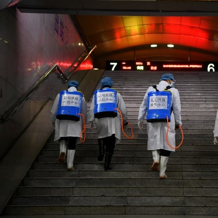 Workers with sanitizing equipment walk up a flight of stairs as they disinfect a railway station while the country is hit by an outbreak of the new coronavirus, in Kunming, Yunnan province, China February 4, 2020. Photo: cnsphoto via Reuters