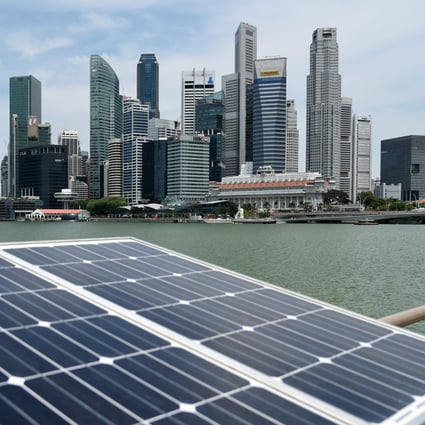 Solar panels used to power walkway lights are positioned along the Marina bay overlooking the skyscrapers of Singapore on April 26, 2016. / AFP PHOTO / ROSLAN RAHMAN