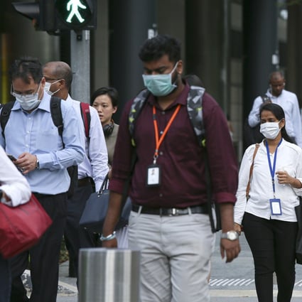 Commuters wearing protective masks walk through the Marina Bay business district in Singapore on Wednesday. Photo: Bloomberg