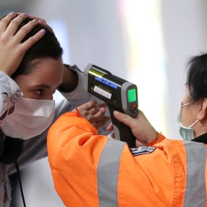 A passenger has her temperature taken at Hong Kong International Airport. The city’s anti-government protests and the Covid-19 outbreak are proving to be catalysts for life decisions among its residents. Photo: Reuters