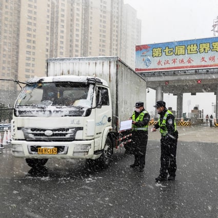 Traffic police officers check a vehicle at a toll station in Wuhan, Hubei province, on Saturday. Photo: Xinhua