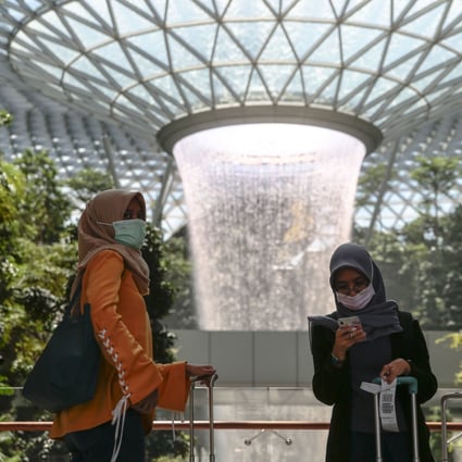 People wearing protective face masks stand near the Rain Vortex at the Jewel Changi Airport mall in Singapore. The Ministry of Health has reported 75 coronavirus cases. Photo: EPA-EFE