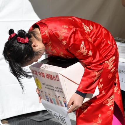 A Japanese girl in Tokyo wearing a red Chinese cheongsam bows deeply to passers-by with a donation box in hands to raise money to help Chinese affected by the coronavirus. Photo: Xinhua