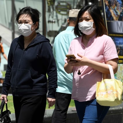 Two women wearing protective face masks, amid concerns over the spread of the COVID-19 coronavirus, walk on the street in Singapore on February 14, 2020. Photo: AFP