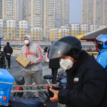 A man wearing protective mask gets a package from a delivery company courier outside a residential area in Beijing on February 12. Photo: EPA-EFE