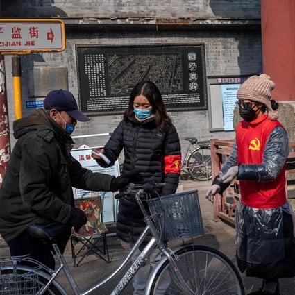 Community volunteers wearing protective face masks and gloves take the temperature of a man on a street in Beijing. Photo: AFP