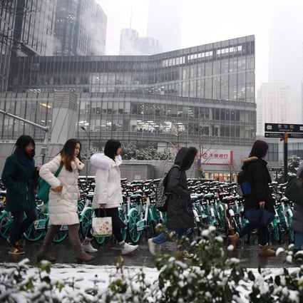 Office workers walk past buildings in Beijing's central business district, as they arrive for work on December 16, 2019. More than half have been telecommuting since the spread of the coronavirus over the Lunar New Year holiday. Photo: Agence France-Presse