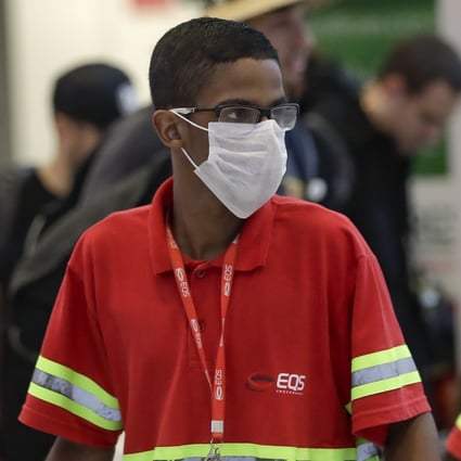 Airport employees wear masks as a precaution against the spread of the coronavirus as they work at Brazil’s Sao Paulo International Airport on Wednesday. Photo: AP