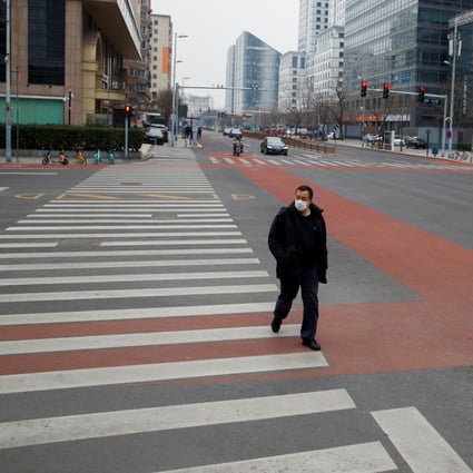 A man crosses the road in the practically deserted central business district in Beijing on February 24. Photo: Reuters