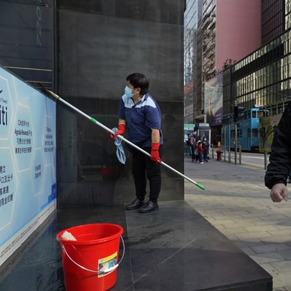 A man wearing face mask walks past a clean woman at a downtown street in Hong Kong on February 17. The Covid-19 disease is likely to spur wider application of technology in real estate market, according to JLL. Photo: AP