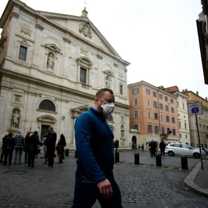 A man wearing a protective mask walks past the Church of St. Louis of the French in Rome. Photo: AFP
