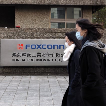 People wearing face masks walk past a building of Foxconn Technology Group in New Taipei City, Taiwan, on February 18. Photo: EPA-EFE