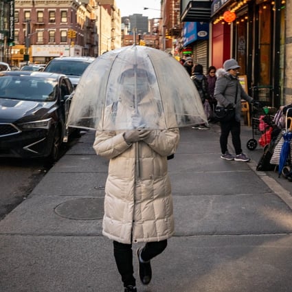 A person wears a protective mask while walking with an umbrella in New York’s Chinatown neighbourhood. Photo: Bloomberg