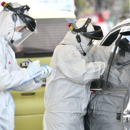 Medical workers wearing protective gear take samples from a driver with suspected coronavirus symptoms at a ‘drive-through’ test facility in South Korea. Photo: AFP