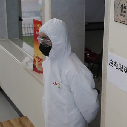 A worker wearing a protective body suit stands near a framed picture of President Xi Jinping at a dairy factory in Beijing on February 27. Photo: EPA-EFE
