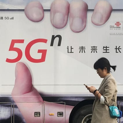 A woman using her smartphone walks past a vehicle covered with a China Unicom 5G advertisement in Beijing in September of last year. China is expected to have 600 million 5G users by 2025. Photo: Reuters