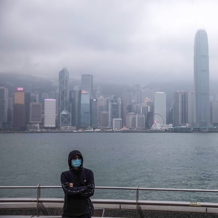 A man wearing a face mask is flanked by the Hong Kong skyline in Tsim Sha Tsui on January 25. The coronavirus epidemic has emptied streets in some of Hong Kong’s busiest areas. Photo: AFP