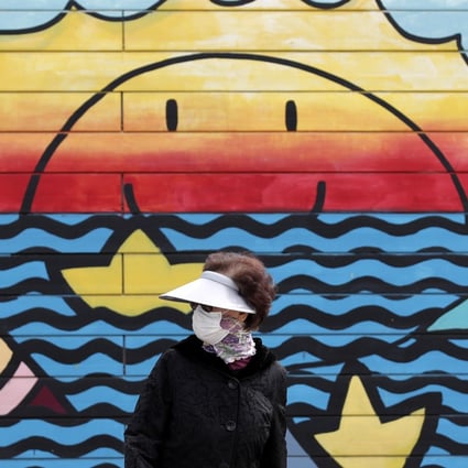 A woman wearing a face mask walks along the Han river at a park in Seoul, South Korea. Photo: AP