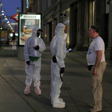 People wearing protective clothes talk with a man at the Gran Via avenue in downtown in Madrid. Photo: AP Photo