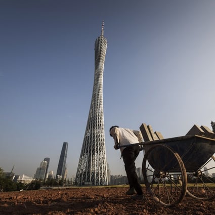 A worker pulls a cart in front of the residential and commercial buildings, including the Canton Tower, in Guangzhou, China, in November 2017. A report published by an investment bank noted that work had resumed at half the building sites among developers it covers. Photo: Bloomberg