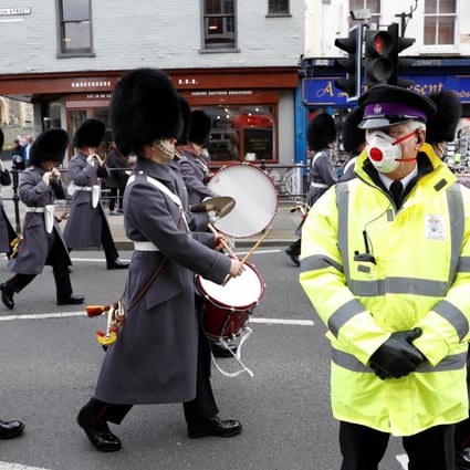 A security guard wearing a face mask stands outside Windsor Castle in the UK as a marching band passes by on Tuesday. Photo: Reuters