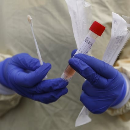 A nurse holds a Covid-19 testing kit at a drive-through station at a hospital in Royal Oak, Michigan. Photo: AP