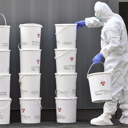 A medical staff member stacks plastic buckets containing medical waste from new coronavirus patients at Dongsan Hospital in Daegu, South Korea. Photo: AP