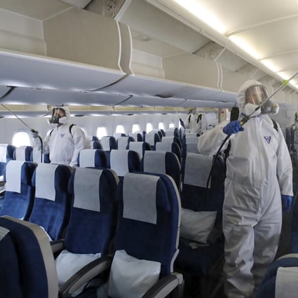 Workers in protective gear disinfect a plane bound for New York Incheon International Airport in South Korea, as the pandemic shifts westwards. Photo: AP