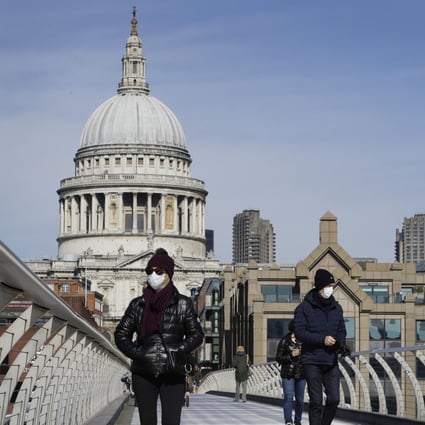 People wear masks as they walk over Millennium Bridge near St Paul's Cathedral in London on Sunday. Photo: AP
