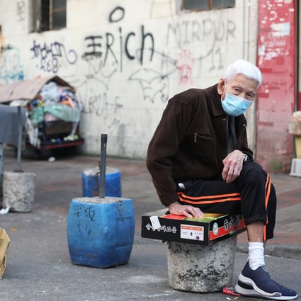 An elderly man sits on a cardboard box in a street in Sham Shui Po. Photo: Xiaomei Chen