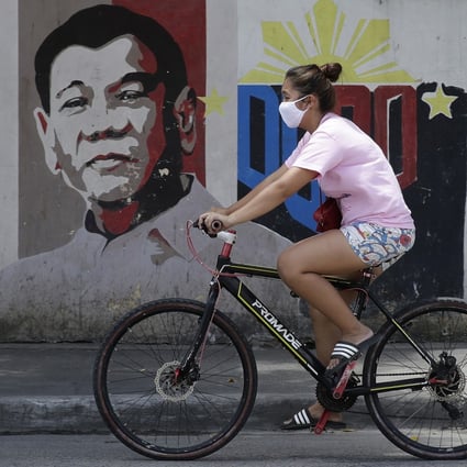 A cyclist rides past a mural of Philippine President Rodrigo Duterte in Manila on March 20, 2020. Photo: AP