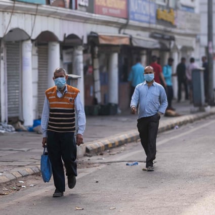 People wearing face masks as a preventive measure against the Covid-19 novel coronavirus walk past closed shops in a market area in New Delhi on March 23, 2020. Photo: AFP