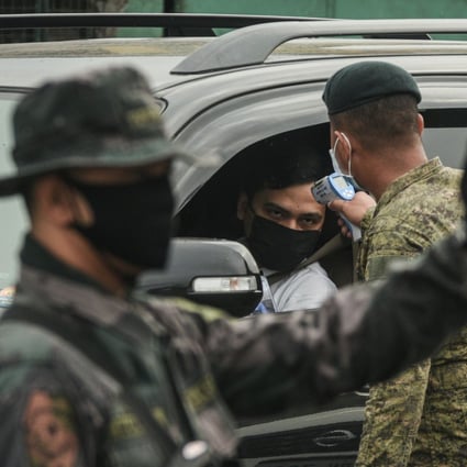 A soldier checks the temperature of a motorist at a coronavirus checkpoint near Manila on Monday. Photo: AFP
