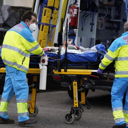 Paramedics wheel a patient from an ambulance into the emergency department of a hospital in Madrid. Photo: Bloomberg