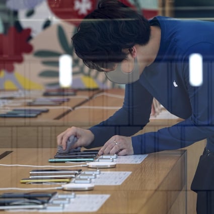 An Apple Store employee wearing a protective mask cleans the screen of an iPhone inside the US technology giant’s store in the Omotesando area of Tokyo, Japan, on March 15. Photo: Bloomberg