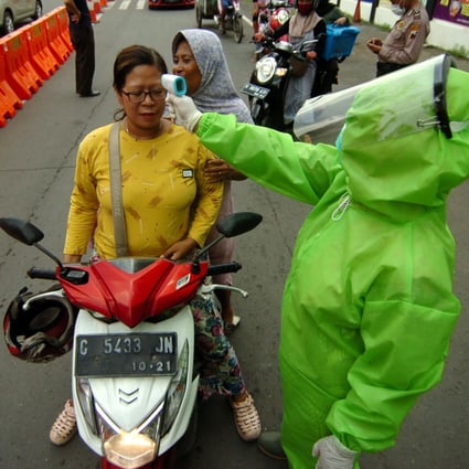 A health worker checks a woman’s temperature in Central Java, Indonesia, on March 31, 2020. Photo: Antara Foto via Reuters