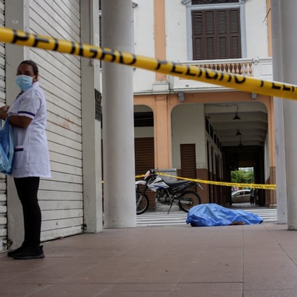 Women stand near a dead body on the pavement in Guayaquil, Ecuador. Photo: Reuters