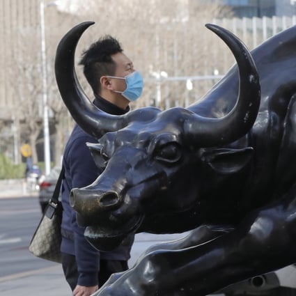 A man wearing a mask walks by a bronze sculpture of a bull in the central business district in Beijing. Photo: EPA-EFE