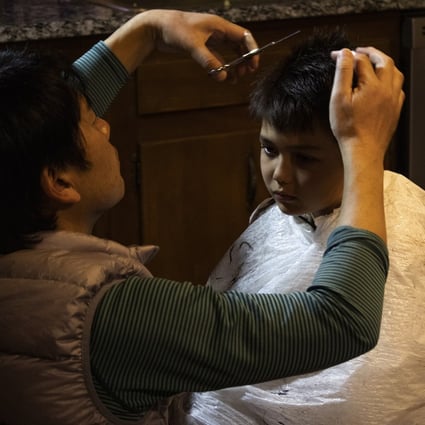 Naoto Ikeda cuts his son Noah’s hair in the kitchen of their home. Photo: AP