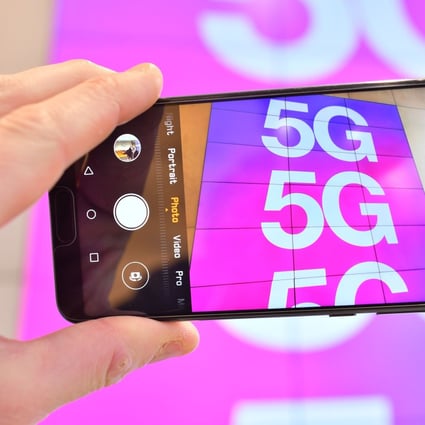 A person poses holding a mobile telephone the camera showing a sign advertising 5G mobile telecommunication in a shop in London on January 28, 2020. Photo: AFP