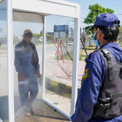 A man walks through a disinfecting booth on a street in Rawalpindi, Pakistan. Photo: AFP