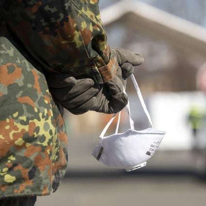 A member of the German armed forces holds a face mask in Gera, Germany. Photo: AP